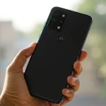 Fx Hand holding Motorola Moto G75 displaying the back design and camera layout photographed against a soft bokeh background in natural daylight 1