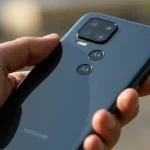 Fx Hand holding Motorola Moto G75 displaying the back design and camera layout photographed against a soft bokeh background in natural daylight 2