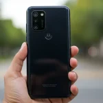 Fx Hand holding Motorola Moto G75 displaying the back design and camera layout photographed against a soft bokeh background in natural daylight 3