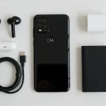 Fx Top down view of Motorola Moto G75 surrounded by tech accessories like wireless earbuds and charger on a minimalist white surface 1