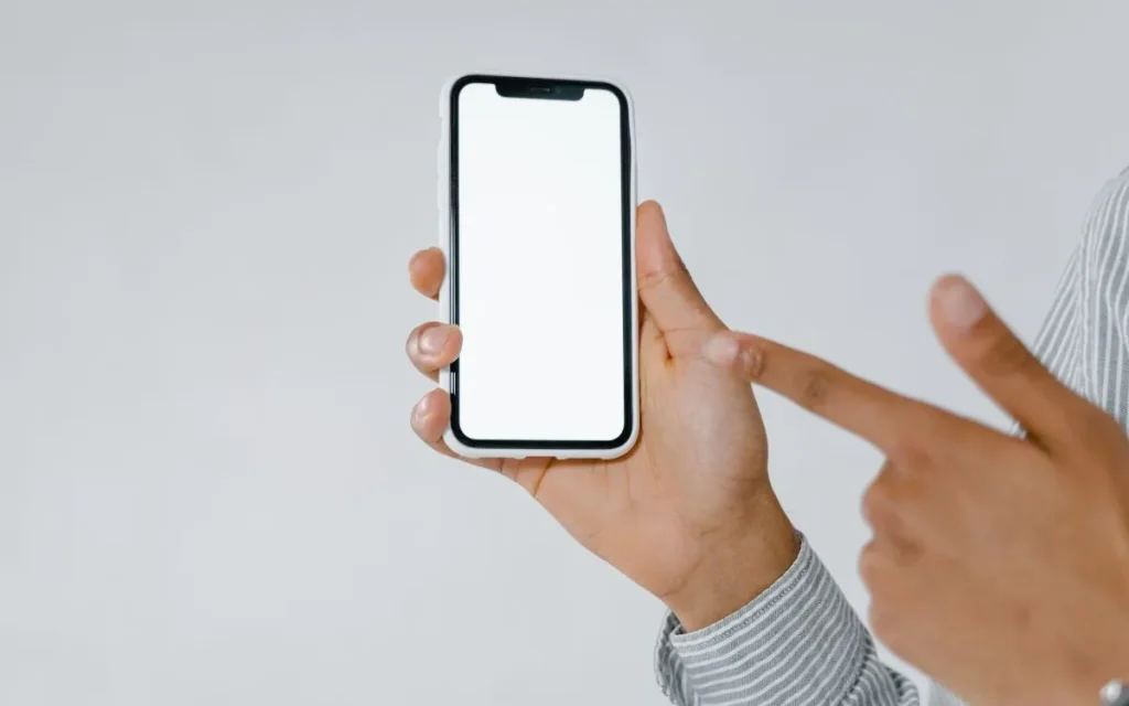 Pessoa segurando celular moderno com tela ligada exibindo aplicativo.