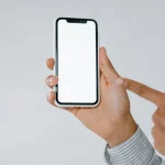 Pessoa segurando celular moderno com tela ligada exibindo aplicativo.