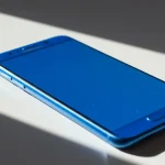 Fx Samsung budget smartphone lying on a clean white surface with soft natural lighting from the side 1