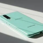 Fx Samsung budget smartphone lying on a clean white surface with soft natural lighting from the side 3