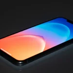 Fx iPhone 16e screen reflection showing colorful abstract patterns device positioned on glass surface studio lighting creating beautiful reflections and refractions 4