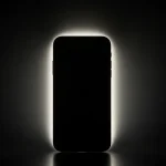 Fx iPhone 16e with dramatic backlighting creating halo effect silhouette style with subtle details visible artistic product photography approach 1