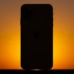 Fx iPhone 16e with dramatic backlighting creating halo effect silhouette style with subtle details visible artistic product photography approach 4