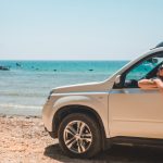 Carro parado frente a praia tomando sol