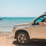 Carro parado frente a praia tomando sol